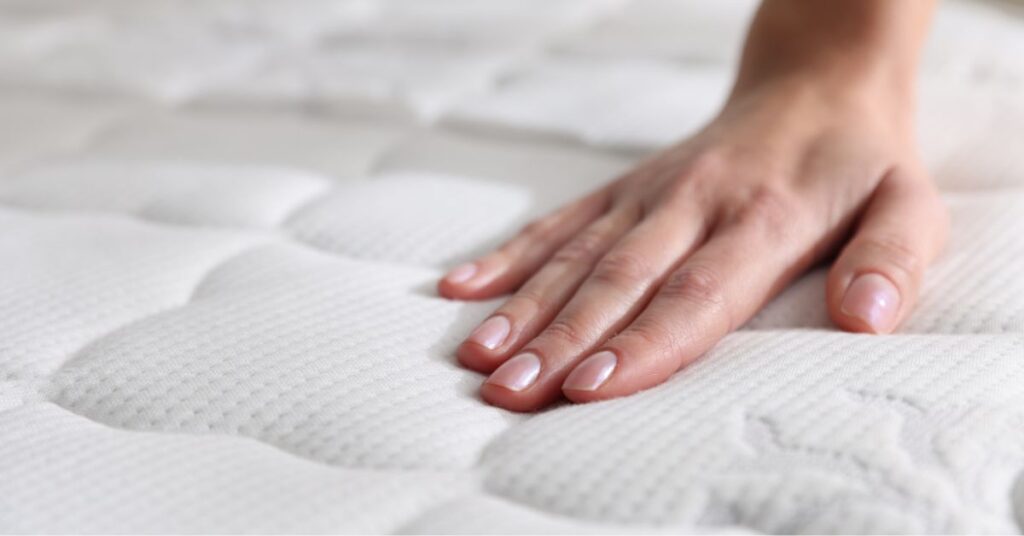 Dłoń na powierzchni materaca przeciwodleżynowego używanego w opiece nad pacjentem leżącym